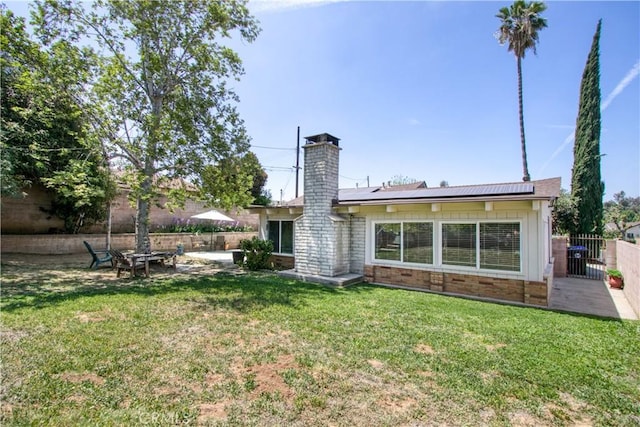 11947 Vivienda Ct, Grand Terrace, CA 92313 - back of property featuring a patio, board and batten siding, a yard, fence, and roof mounted solar panels