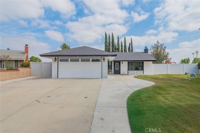 view of front of property featuring fence, concrete driveway, an attached garage, brick siding, and a front yard