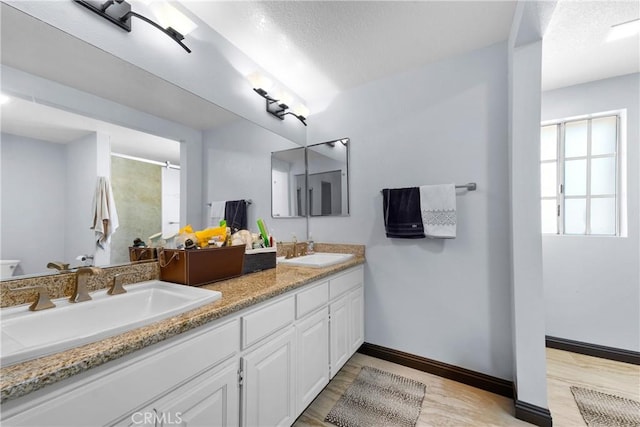 bathroom with a sink, double vanity, an enclosed shower, and wood finished floors