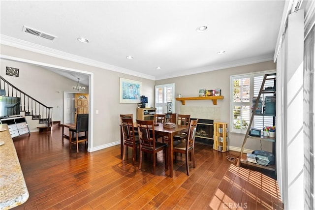 dining area with a tiled fireplace, visible vents, baseboards, and stairs