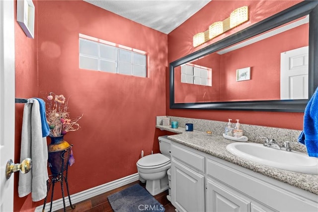 bathroom with vanity, toilet, baseboards, and wood finished floors