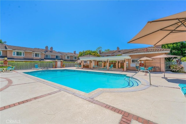 community pool with a patio area, a residential view, and fence
