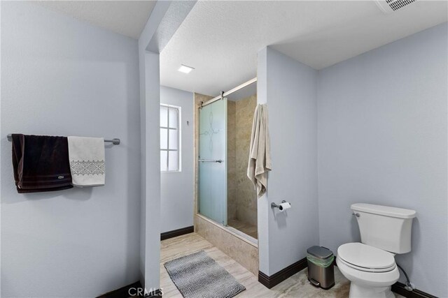 full bath featuring a stall shower, baseboards, and toilet