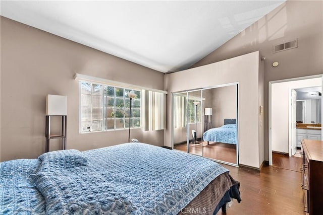 bedroom featuring a closet, vaulted ceiling, dark wood-style flooring, and visible vents
