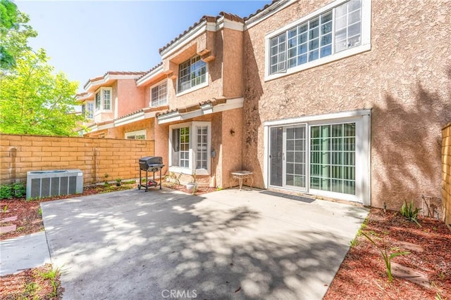 back of house featuring central AC unit, stucco siding, fence, and a patio area