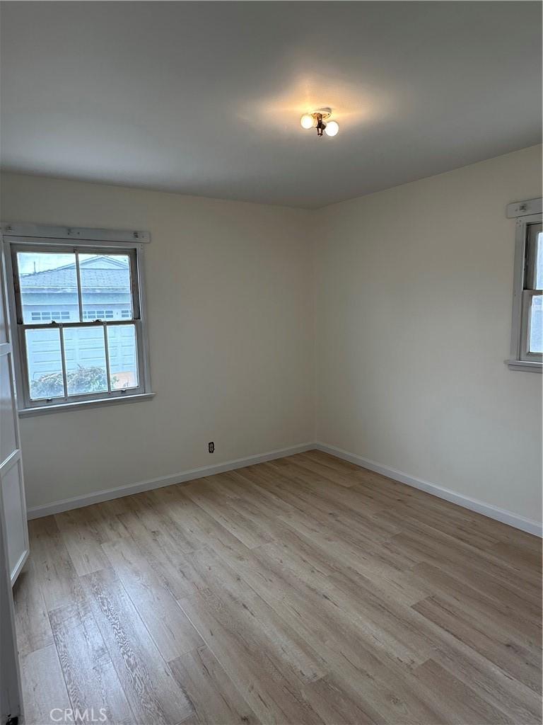 unfurnished room with baseboards and light wood-style floors