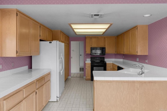 kitchen featuring wallpapered walls, visible vents, a sink, and black appliances