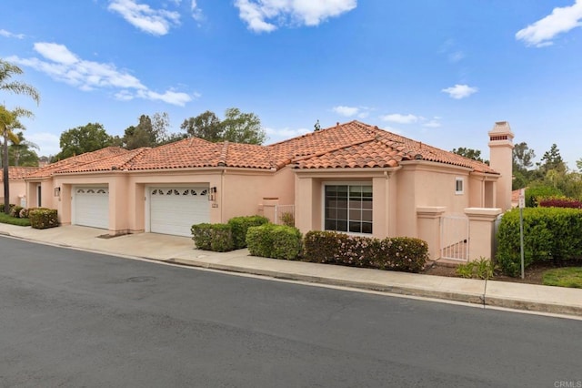 mediterranean / spanish-style house with concrete driveway, stucco siding, a tiled roof, and an attached garage