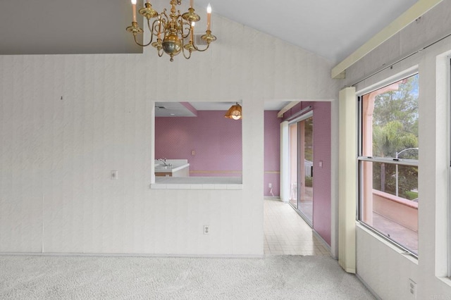 carpeted empty room with an inviting chandelier and vaulted ceiling