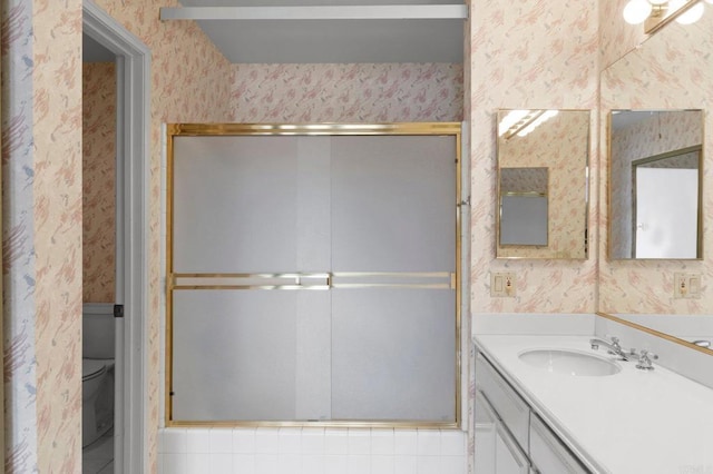 full bath featuring toilet, vanity, wallpapered walls, and a stall shower
