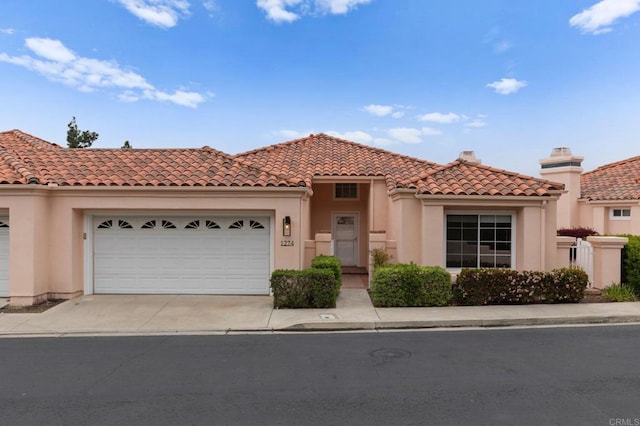 mediterranean / spanish-style home featuring a tile roof, stucco siding, a garage, and concrete driveway