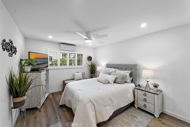 bedroom featuring recessed lighting, baseboards, wood finished floors, and a wall mounted air conditioner