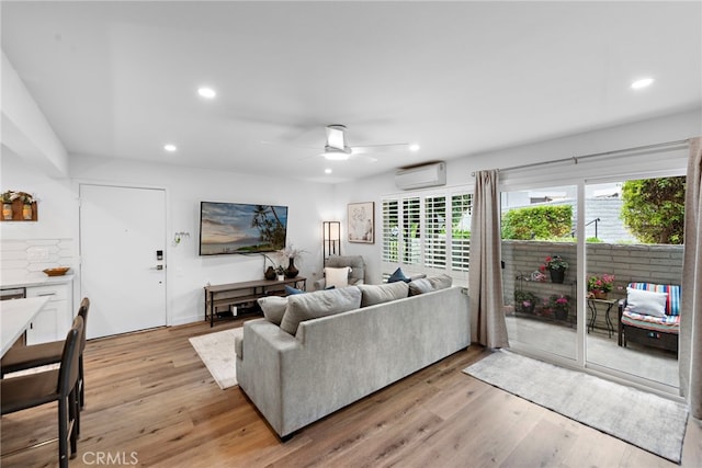 living room with recessed lighting, light wood finished floors, ceiling fan, and a wall unit AC