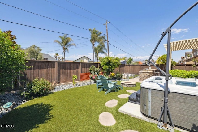 view of yard with a fenced backyard, a hot tub, and a fire pit