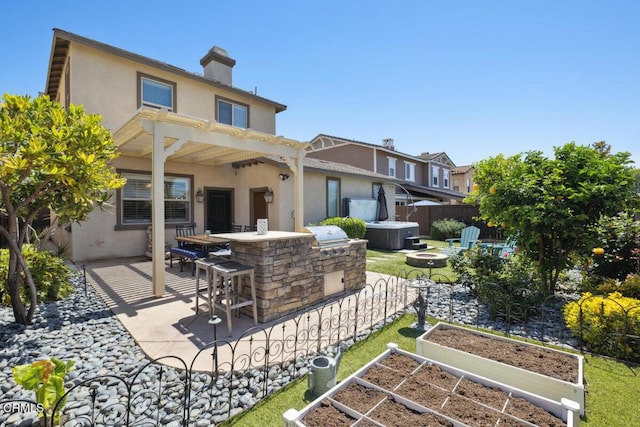 rear view of property featuring fence, outdoor dry bar, stucco siding, a patio area, and a fire pit