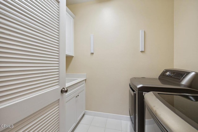 laundry room with light tile patterned floors, baseboards, cabinet space, and washer and clothes dryer