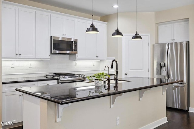 kitchen featuring stainless steel appliances, a kitchen bar, a sink, and tasteful backsplash