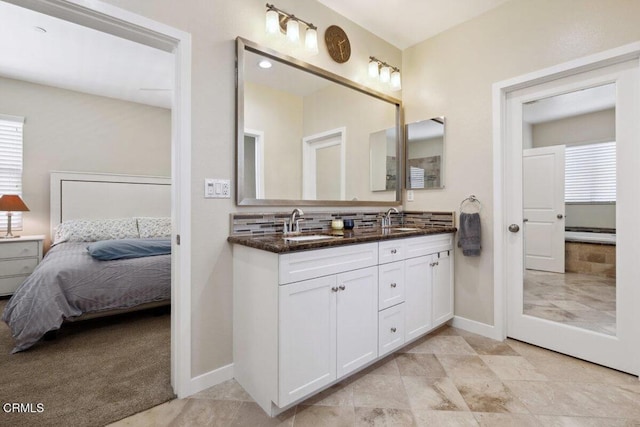ensuite bathroom with a sink, baseboards, ensuite bathroom, and double vanity
