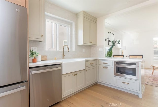 3540 S Sycamore Ave, Los Angeles, CA 90016 - kitchen featuring a sink, light countertops, appliances with stainless steel finishes, a peninsula, and light wood finished floors