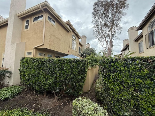 view of side of property with a chimney and stucco siding