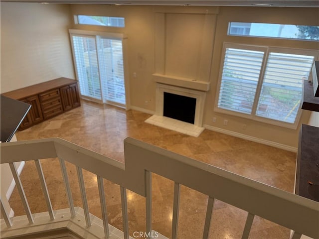 unfurnished living room with a fireplace with raised hearth and baseboards