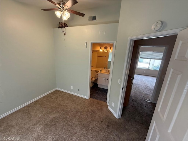 unfurnished bedroom with dark colored carpet, baseboards, ensuite bathroom, and visible vents