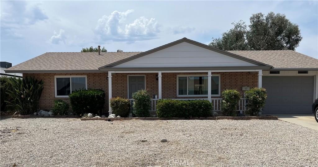 26231 Pine Valley Rd, Menifee, CA 92586 - ranch-style home featuring a garage, brick siding, covered porch, concrete driveway, and roof with shingles