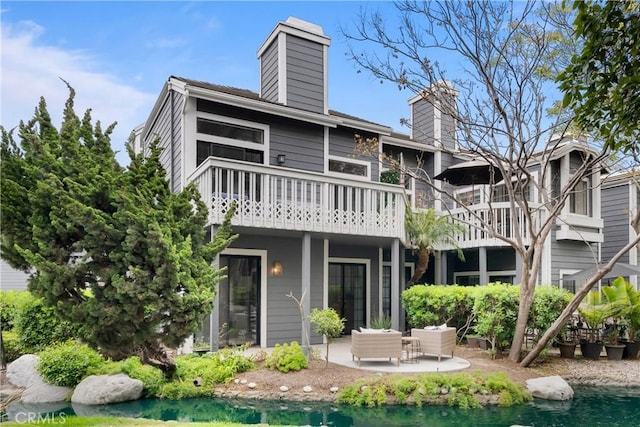 rear view of property featuring a patio, a balcony, and a chimney