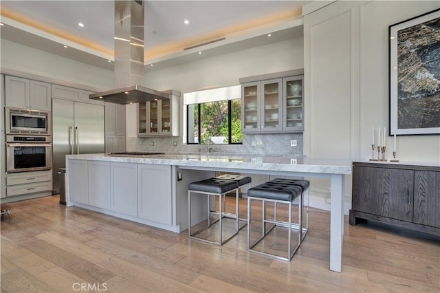 4737 Dunas Ln, Tarzana, CA 91356 - kitchen featuring built in appliances, island exhaust hood, light wood-type flooring, decorative backsplash, and recessed lighting