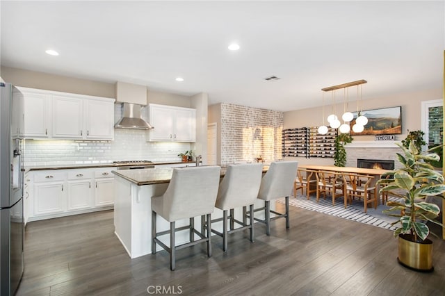 33081 Yucca St, Temecula, CA 92592 - kitchen featuring wall chimney exhaust hood, stainless steel appliances, white cabinetry, a breakfast bar, and dark wood finished floors