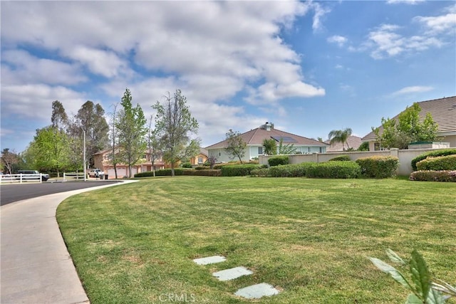 view of home's community featuring fence and a lawn