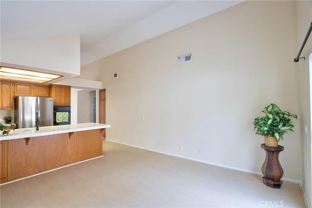 kitchen with visible vents, tile countertops, freestanding refrigerator, baseboards, and a breakfast bar area