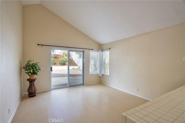 spare room featuring baseboards, wood finished floors, and high vaulted ceiling