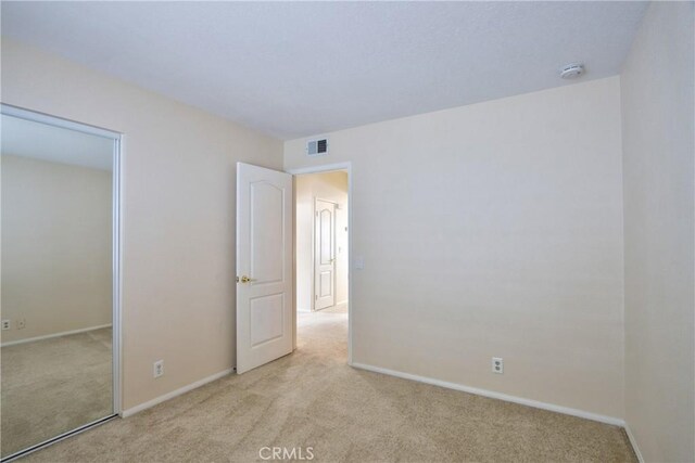 unfurnished bedroom with baseboards, visible vents, carpet, and a closet