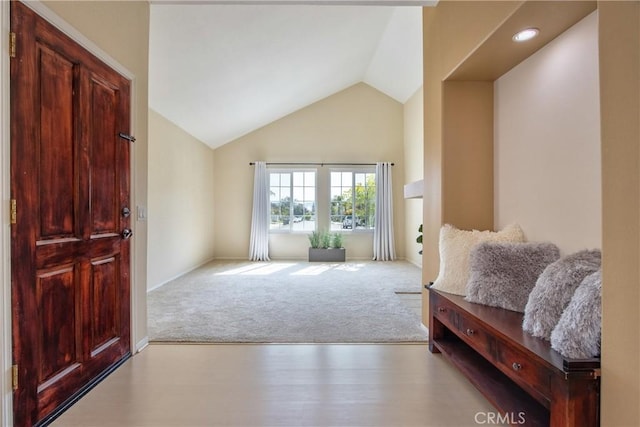 carpeted foyer entrance with vaulted ceiling and wood finished floors