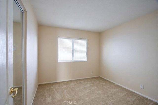 empty room featuring light carpet and baseboards