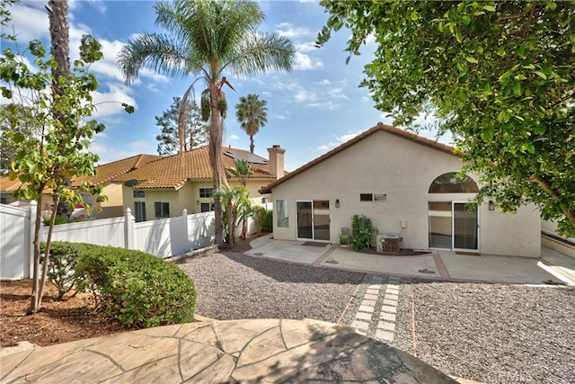 back of house featuring a tiled roof, central AC, fence, a patio, and stucco siding