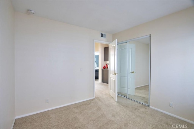 unfurnished bedroom featuring baseboards, visible vents, a closet, and light colored carpet