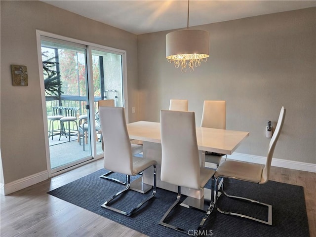 dining room featuring wood finished floors, baseboards, and a notable chandelier