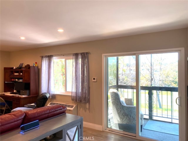 living room with recessed lighting, wood finished floors, baseboards, and a wall unit AC