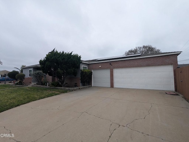 636 N C St, Oxnard, CA 93030 - view of front of house featuring a front yard, brick siding, solar panels, and a garage