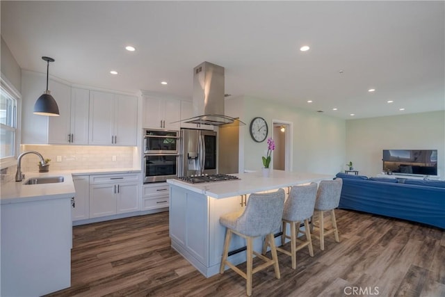 kitchen with island exhaust hood, a sink, white cabinetry, and appliances with stainless steel finishes