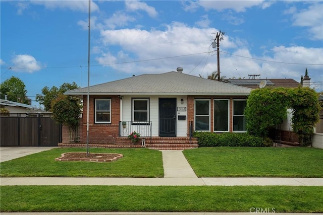 bungalow-style home with brick siding, a front lawn, and fence