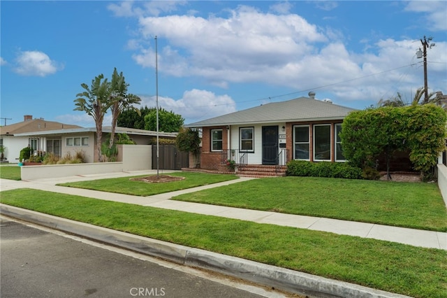view of front of house featuring brick siding, a front yard, and fence