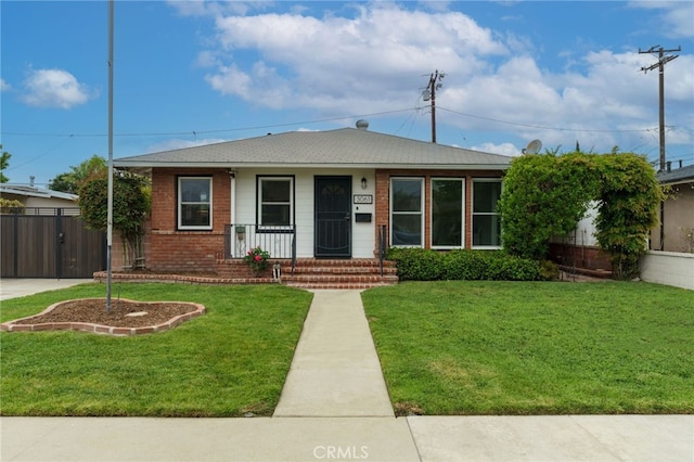 bungalow with a front lawn, brick siding, fence, and covered porch