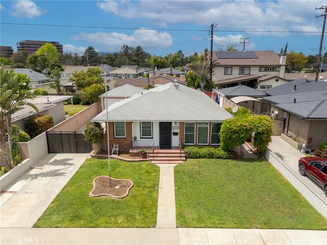 ranch-style house with a gate, a front lawn, driveway, brick siding, and a residential view