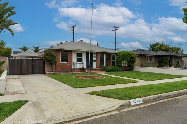 view of front of house featuring a gate, driveway, a front yard, and brick siding