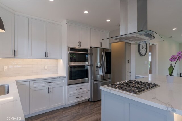 kitchen featuring tasteful backsplash, island range hood, white cabinets, appliances with stainless steel finishes, and recessed lighting