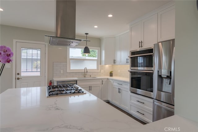 kitchen with recessed lighting, stainless steel appliances, island range hood, a sink, and decorative backsplash