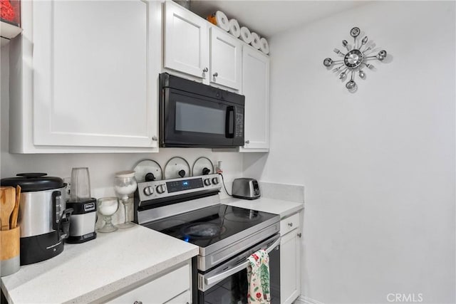 kitchen with black microwave, stainless steel electric range oven, and white cabinets